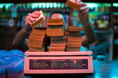 Một chủ tiệm b&aacute;nh ở Caracas đang c&acirc;n tiền. Ảnh:&nbsp;Bloomberg
