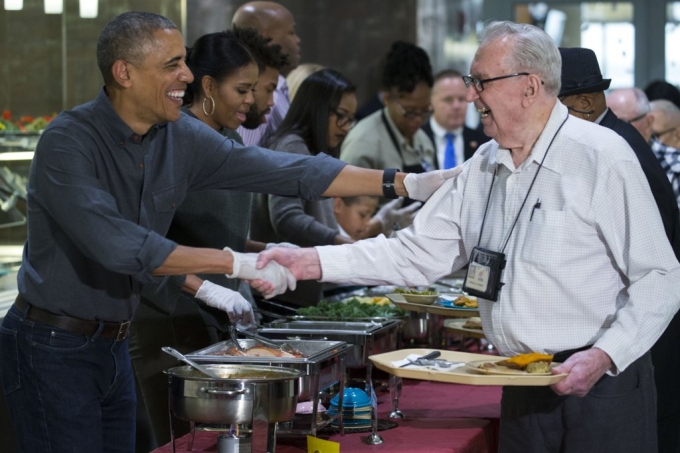 Gia đ&igrave;nh Tổng thống Obama vui vẻ phục vụ bữa tối cho c&aacute;c cựu binh. Đệ nhất phu nh&acirc;n Michelle phục vụ m&oacute;n rau ch&acirc;n vịt v&agrave; đậu. (Ảnh: AP)