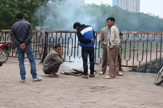 Những người xe &ocirc;m truyền thống tr&ecirc;n đường Ho&agrave;ng Quốc Việt đang đốt lửa để sưởi ấm.