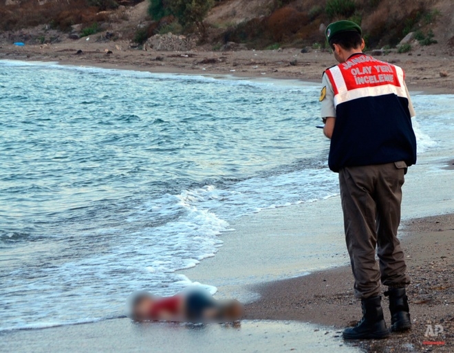 &nbsp;Một sĩ quan b&aacute;n qu&acirc;n sự điều tra hiện trường trước khi di chuyển thi thể của cậu b&eacute; 3 tuổi người Syria Aylan Kurdi h&ocirc;m 2/9. X&aacute;c em dạt v&agrave;o bờ biển Bodrum, Thổ Nhĩ Kỳ, v&igrave; bị chết đuối c&ugrave;ng mẹ v&agrave; anh trai tr&ecirc;n một con thuyền tị nạn.&nbsp;Ảnh:&nbsp;AP.