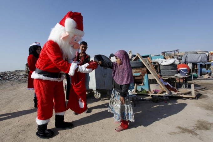 Một &ocirc;ng gi&agrave; Noel tặng qu&agrave; cho những đứa trẻ ở khu d&acirc;n cư ngh&egrave;o tại Najaf, ph&iacute;a nam thủ đ&ocirc; Baghdad. (Ảnh: Reuters)