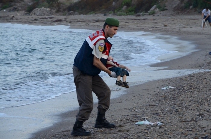 Nh&acirc;n vi&ecirc;n cứu hộ Thổ Nhĩ Kỳ bế thi thể b&eacute; Alan Kurdi dạt v&agrave;o bờ biển khi chiếc thuyền chở gia đ&igrave;nh em đến đảo Kos, Hy Lạp, bị lật giữa biển ng&agrave;y 2/9 của t&aacute;c giả Nilufer Demir. Ảnh: Reuters.