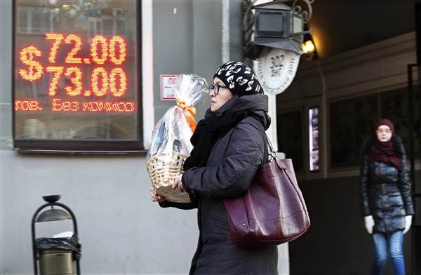 Một phụ nữ Nga x&aacute;ch theo giỏ qu&agrave; tr&ecirc;n đường phố Moscow h&ocirc;m 29/12. Ảnh: EPA