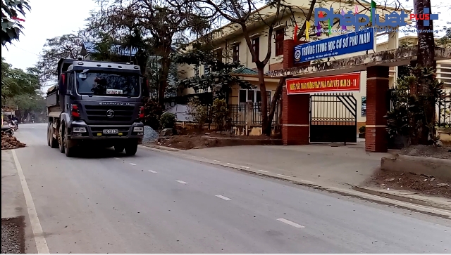 Xe tải chạy qua trường trung học cơ sở.