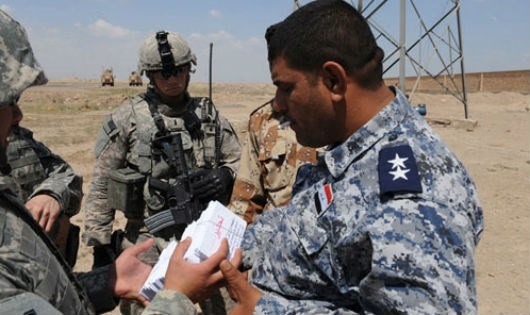 Nh&acirc;n vi&ecirc;n Sgt. Michael Bautista từ C&ocirc;ng ty Điều h&agrave;nh 301 T&acirc;m l&yacute;, tờ rơi tay cho một sĩ quan cảnh s&aacute;t Iraq để tặng cho những người d&acirc;n địa phương, v&agrave;o ng&agrave;y 10/4/2009, tại Baghdad, Iraq. (Nguồn: psywar.org)