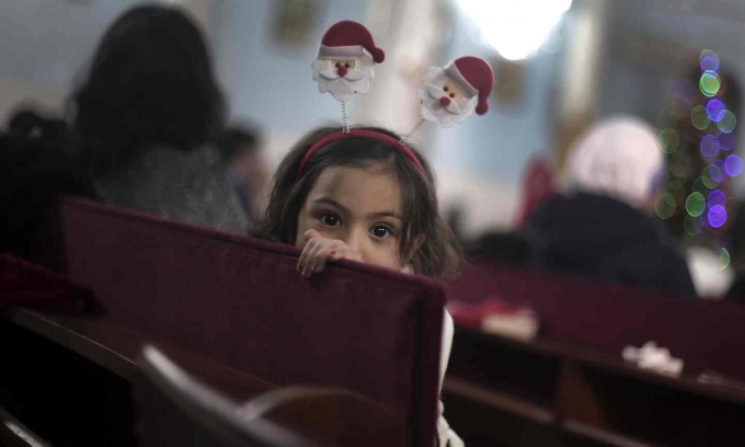 Một b&eacute; g&aacute;i người Palestine đang chuẩn bị l&agrave;m lễ đ&ecirc;m Gi&aacute;ng sinh tại nh&agrave; thờ Holy Family Catholic, Palestine. (Ảnh: Khalil Hamra / AP)