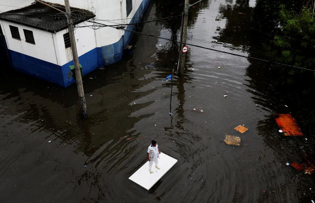 Một người đ&agrave;n &ocirc;ng sử dụng mặt b&agrave;n để lướt tr&ecirc;n đường ngập nước sau trận mưa lớn ở Sao Paulo, Brazil ng&agrave;y 7/4.
