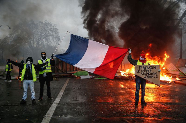 Người biểu t&igrave;nh &Aacute;o v&agrave;ng cầm cờ Ph&aacute;p phản đối ch&iacute;nh quyền Macron tại Paris. (Ảnh: AFP)