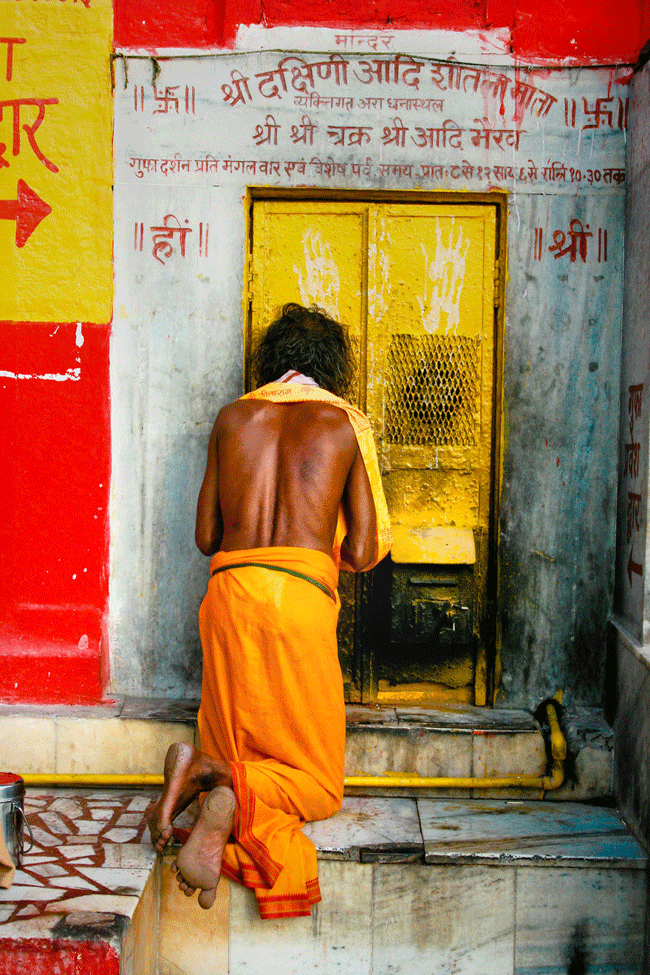 Một người đ&agrave;n &ocirc;ng cầu nguyện trước cửa một ng&ocirc;i đền của th&agrave;nh phố huyền thoại Varanasi, Ấn Độ