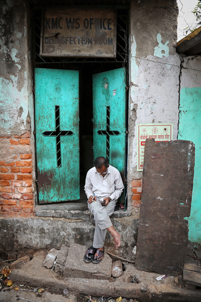 Khoảnh khắc một người đ&agrave;n &ocirc;ng kiểm tra điện thoại di động gần ga Howrah ở Kolkata, Ấn Độ khiến ai cũng ấn tượng về c&aacute;nh cửa xanh ph&iacute;a sau.