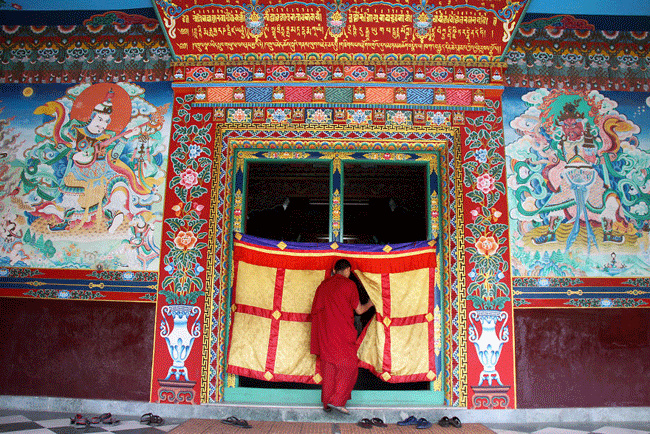 Một khoảnh khắc b&igrave;nh y&ecirc;n trong một khu phố qu&aacute; đ&ocirc;ng đ&uacute;c v&agrave; ồn &agrave;o khi một tu sĩ Phật gi&aacute;o v&agrave;o ph&ograve;ng cầu nguyện của tu viện Tharlam ở Boudhanath, Nepal
