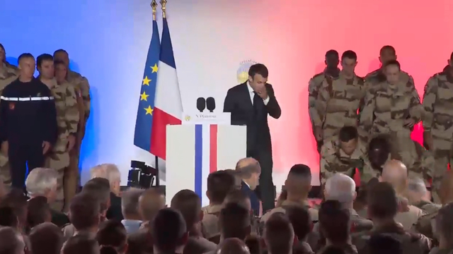Tổng thống Macron bất ngờ khi một binh sĩ ngất xỉu b&ecirc;n cạnh. (Ảnh: RT)