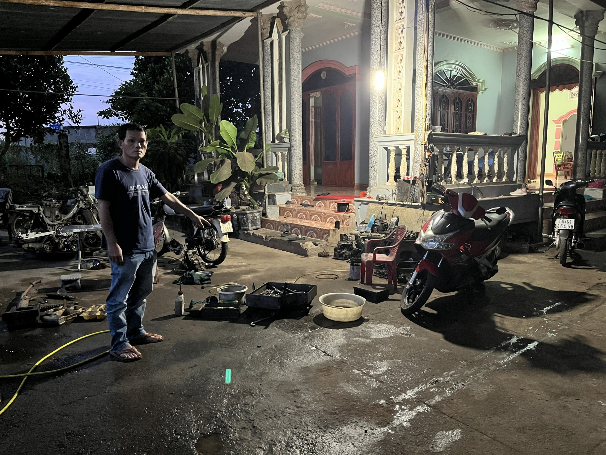 ông Huỳnh Tấn Minh, cha của Tài đang đưa PV đến tiệm sửa xe máy của Toàn.
